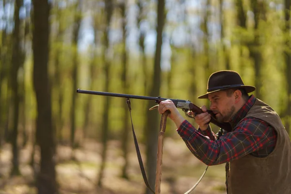 Lovec míří puškou na kořist v lese. — Stock fotografie