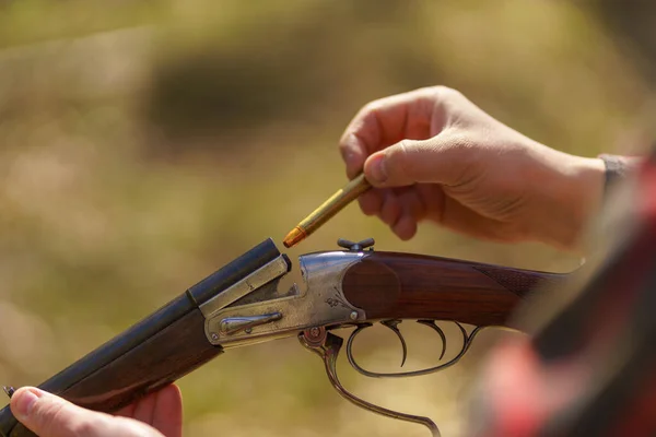 Närbild av jägare man laddar patronen på gevär pistol i skogen. — Stockfoto
