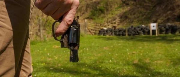 Oigenkännlig man med revolver redo att skjuta mål på skjutbanan utomhus. — Stockfoto
