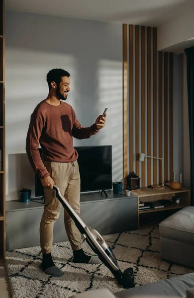 Ein Junger Mann Staubsaugt Teppich Wohnzimmer — Stockfoto