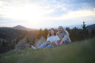 Mutlu bir büyük anne ve genç bir torun bahar günü doğada sarılıyor..