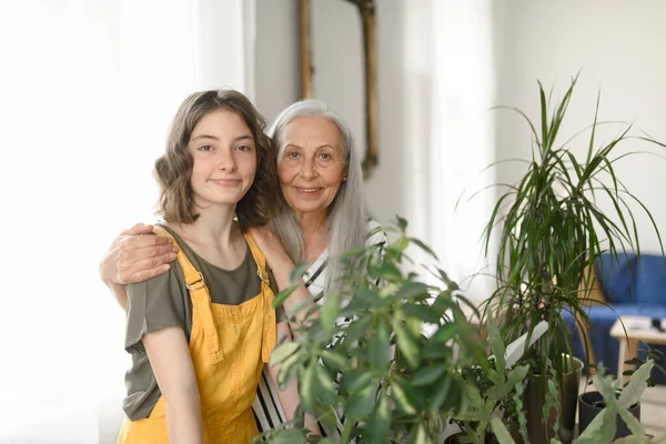 Ergen Torunu Olan Yaşlı Bir Büyükanne Evde Bitkilerle Ilgileniyor — Stok fotoğraf