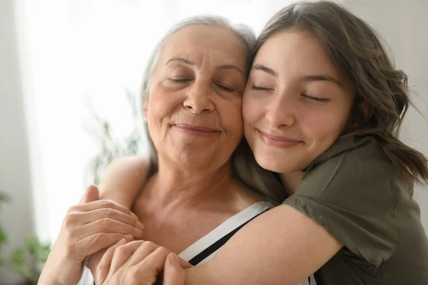 Senior Grandmother Teenage Granddaguhter Hugging Together Home — Stock Photo, Image