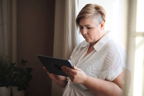 Overweight Woman White Shirt Standing Window Using Tablet — Stock Photo, Image