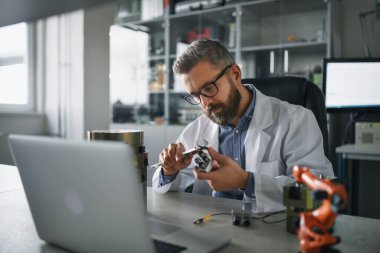 Modern robotik kol analizi üzerinde çalışan bir robot mühendisi laboratuvarda oturuyor..