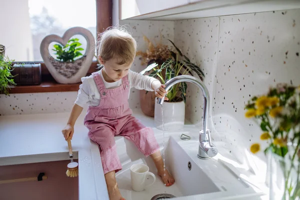 Uma Garotinha Sentada Balcão Cozinha Lavando Xícara Pia Cozinha — Fotografia de Stock