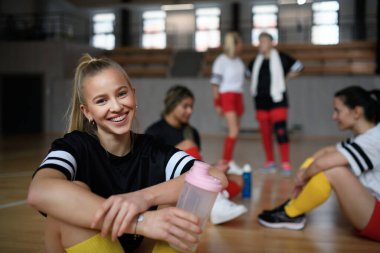 Bir grup genç ve yaşlı kadın, spor takımındaki oyuncular maçtan sonra oturup dinleniyorlar..