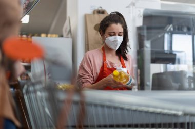 Bir kasiyer süpermarkette yağ şişesini tarıyor..