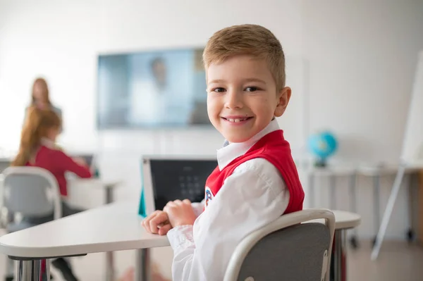 Retrato Estudante Feliz Vestindo Uniforme Escolar Sentado Sala Aula Sorrindo — Fotografia de Stock