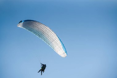Mavi gökyüzünde bir paraglider. Paraşüt üzerinde uçan sporcu..