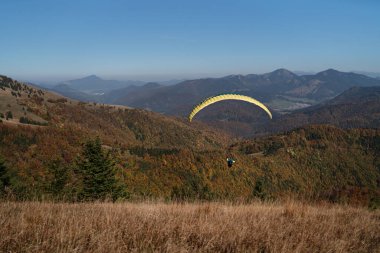 Arka planda dağ ile mavi gökyüzünde uçan bir paraglider..