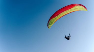 Mavi gökyüzünde bir paraglider. Paraşüt üzerinde uçan sporcu..