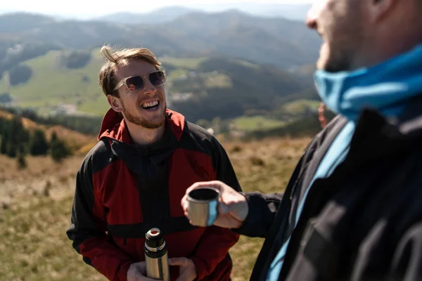 两个滑翔伞运动员站在山顶上喝茶 — 图库照片