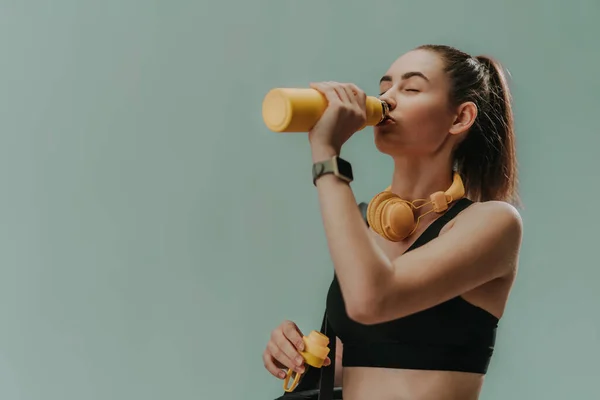 Ung Sportig Kvinna Sportkläder Med Trådlöst Headset Dricka Från Flaska — Stockfoto