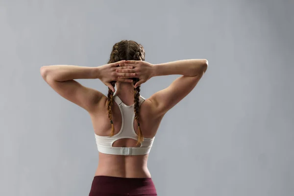 身穿运动服的年轻女子在灰色背景下伸展手臂的后视图 复制空间 — 图库照片