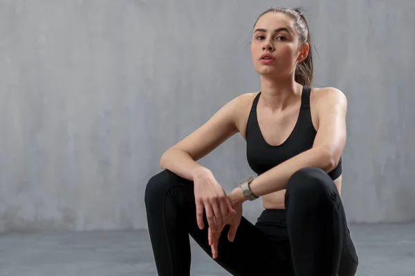 Uma Jovem Mulher Esportiva Esportes Sentado Contra Fundo Cinza Espaço — Fotografia de Stock