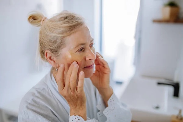 Beautiful Senior Woman Bathrobe Applying Eye Patches Puffiness While Looking — Stok Foto