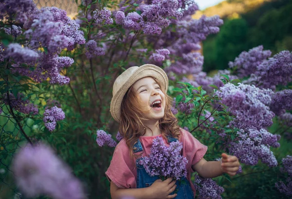一个快乐的小女孩在自然界中绽放的紫丁香草甸的画像 — 图库照片