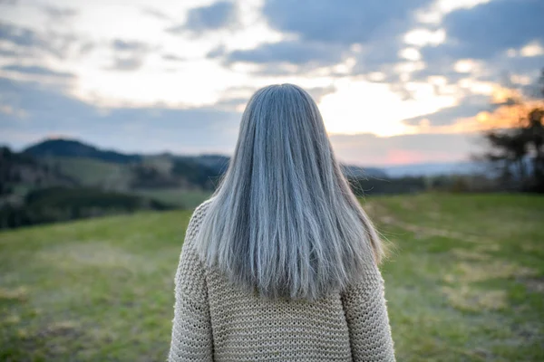 春の日に公園で長い灰色の髪のシニア女性のリアビュー — ストック写真