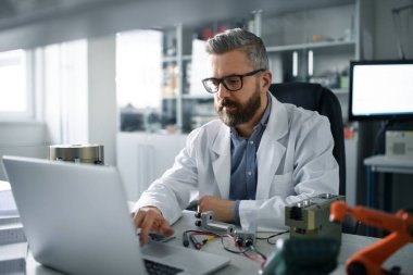 Modern robotik kol desing üzerinde çalışan bir robotik mühendis laboratuvar masasında oturuyor..