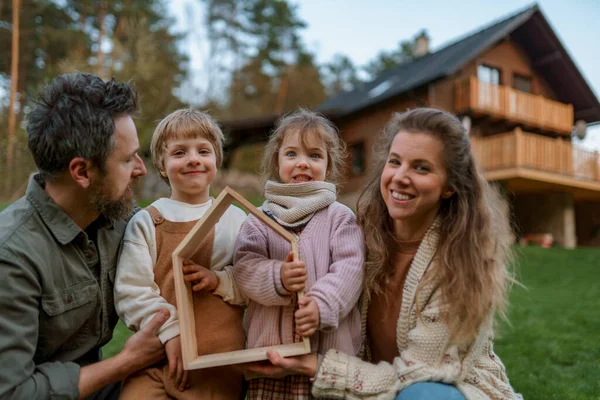 Happy Family Standing Modern House Smiling Looking Camera — Stok Foto