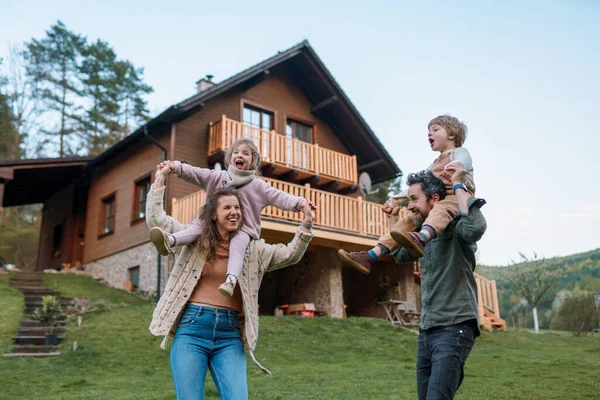 Glückliche Eltern Mit Kleinen Kindern Auf Huckepack Laufen Und Amüsieren — Stockfoto