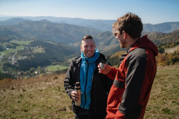 山の上に二人のパラグライダー男が立ってお茶を飲んで — ストック写真