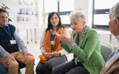 Bir grup kıdemli insan terapi seansı sırasında aynı yerde oturup bazı sorunları tartışıyorlar.
