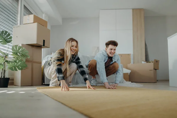 Cheerful Young Couple New Apartment Rolling Out Carpet Conception Moving — Stock Photo, Image
