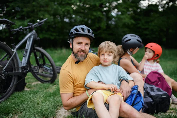 夏に公園の芝生の上に座って 自転車に乗って休んでいる小さな子供のいる若い家族 — ストック写真