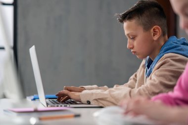 Okulda bilgisayar kullanan bir çocuğun yan görüntüsü.