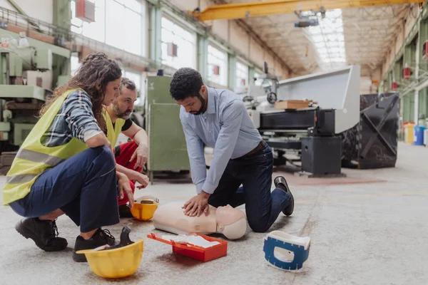 A male instructor showing first medical aid on doll during training course indoors