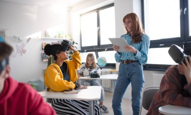 VR gözlüklü öğrencilere ders veren mutlu lise öğretmeni.