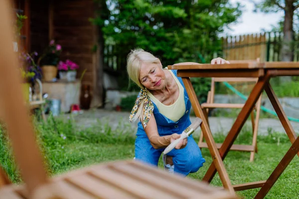 Äldre Kvinna Städar Trädgårdsmöbler Och Gör Trädgården Klar För Sommaren — Stockfoto