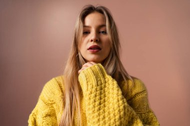 Pembe arka planda poz veren genç sarışın bir kadının moda stüdyosu portresi.