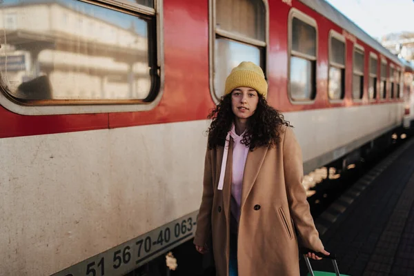 一个带着行李站在月台上坐火车的年轻女旅行家 — 图库照片