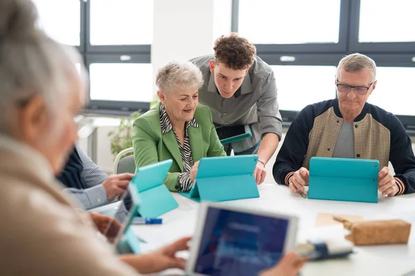 A group of seniors attending IT class in community centre with teacher