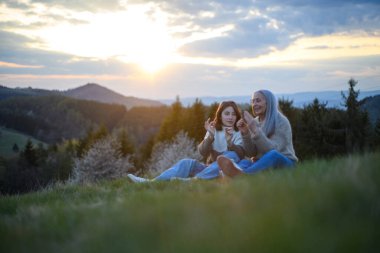 Mutlu bir büyük anne ve genç torunu bahar günü çimlerde oturup ıslık çalıyorlar..