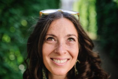 Parktan samimi bir kadın portresi. Genç bir kadın kameraya bakıp gülümsüyor..