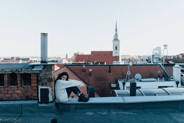 街の景色を眺めながら屋根の上に座っている不幸な若い女性 — ストック写真