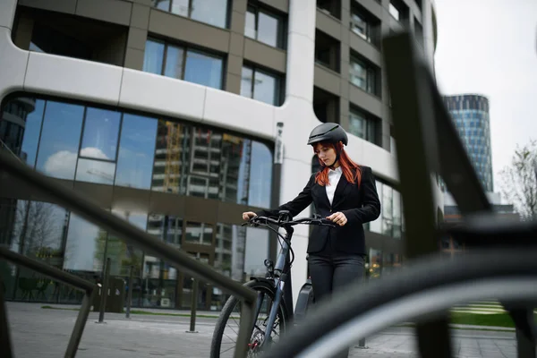 A portrait of businesswoman commuter on the way to work with bike, sustainable lifestyle concept.