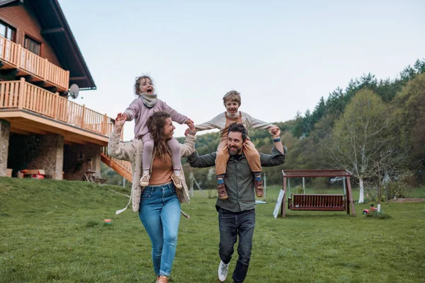 Glückliche Eltern Mit Kleinen Kindern Auf Huckepack Laufen Und Amüsieren — Stockfoto