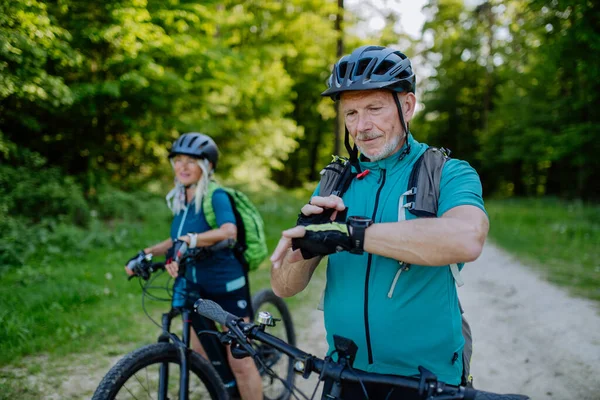 夏の公園で自転車に乗っているアクティブなシニアカップルの肖像画 スポーツスマートウォッチを見て 彼らのパフォーマンスをチェック — ストック写真