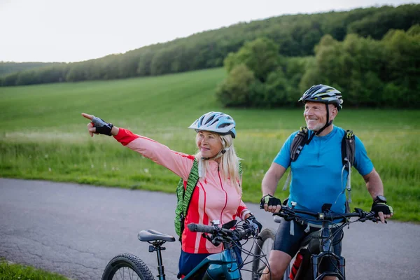 夏の公園 健康的なライフスタイルのコンセプトで道路上の電動自転車に乗るアクティブなシニアカップル — ストック写真