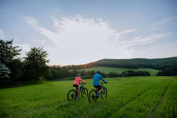 夏の公園を通る電動自転車に乗るアクティブなシニアカップル 健康的なライフスタイルのコンセプト — ストック写真