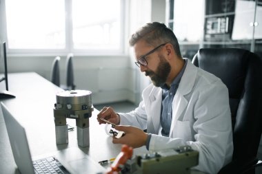 Modern robotik kol analizi üzerinde çalışan bir robot mühendisi laboratuvarda oturuyor..