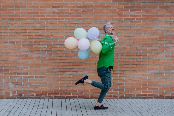 Zabawny Portret Szczęśliwego Energicznego Dojrzałego Mężczyzny Trzymającego Balony Biegającego Ulicy — Zdjęcie stockowe