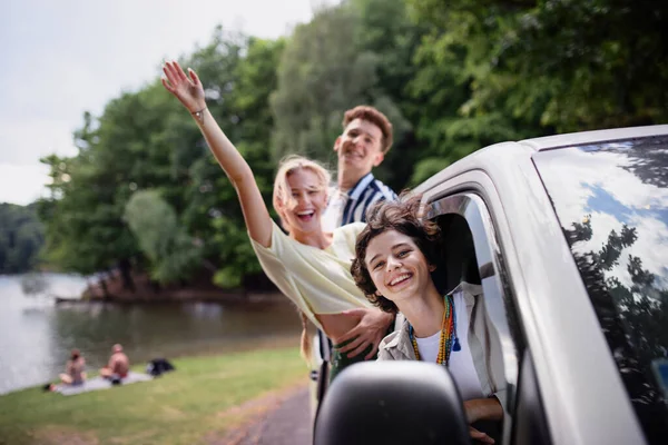 Young Friends Travelling Together Car Looking Window Waving Smiling Summer — Fotografia de Stock