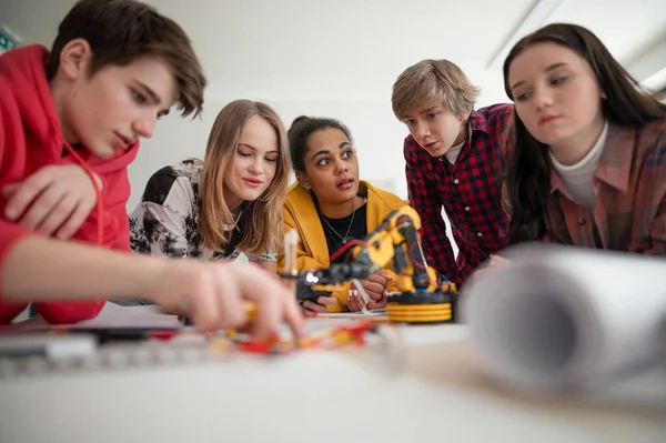 ロボット教室で電気玩具やロボットを構築しプログラミングする学生のグループ — ストック写真