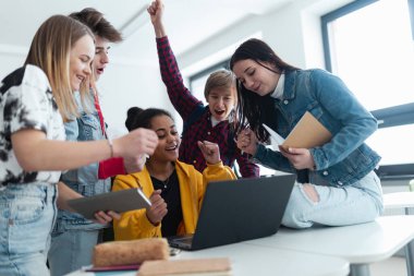 Lise öğrencileri sınıflarında yan yana oturur, dizüstü bilgisayar kullanır ve ders aralarında konuşurlar..